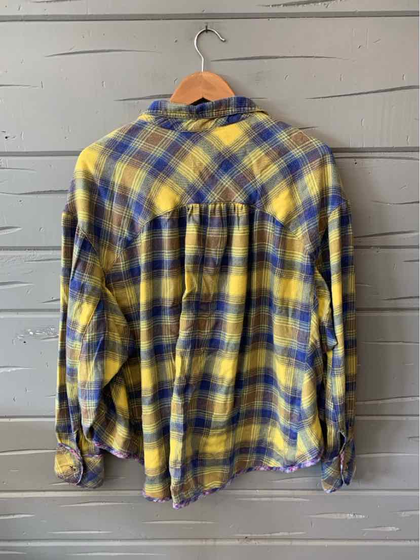 Yellow and blue plaid flannel shirt in large size with long sleeves, hanging on wooden hanger.