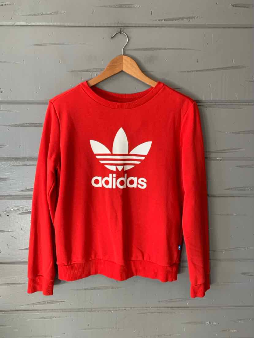 Red Adidas crewneck sweatshirt with a white trefoil logo and long sleeves, hanging on a wooden hanger.