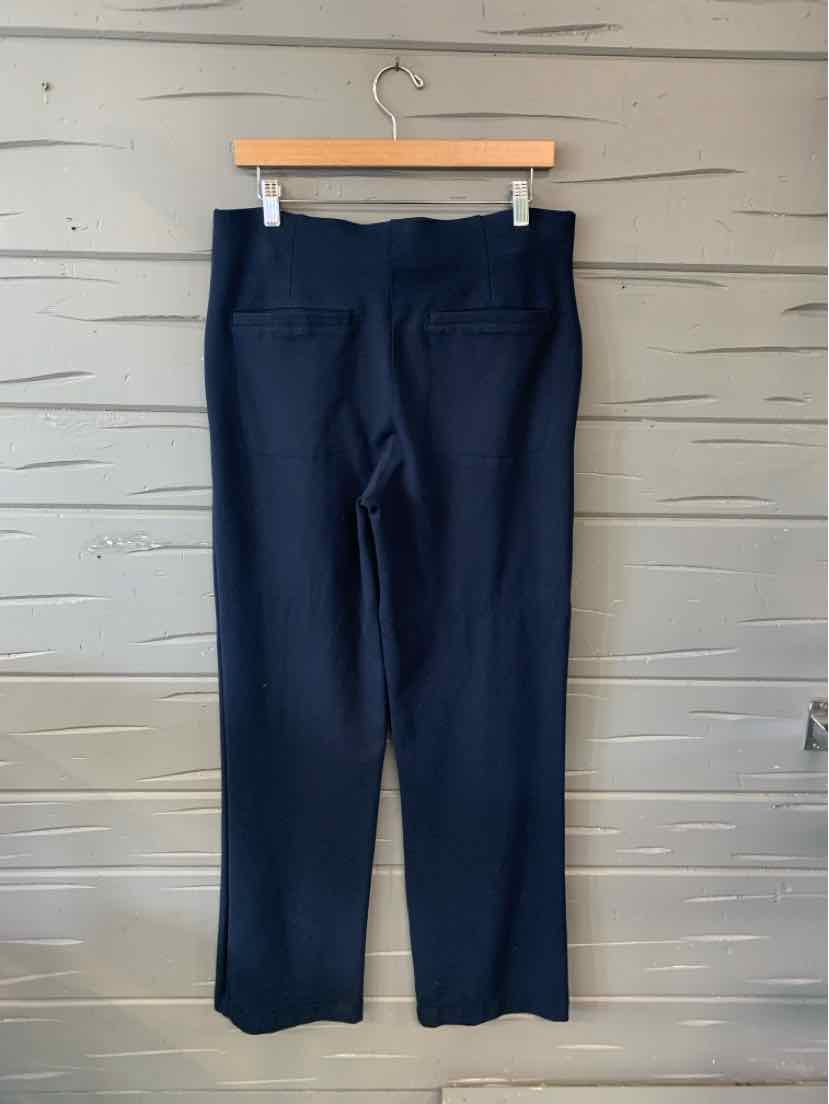 Black straight-leg pants with high waist and smooth fabric hanging on wooden hanger against gray wooden wall.