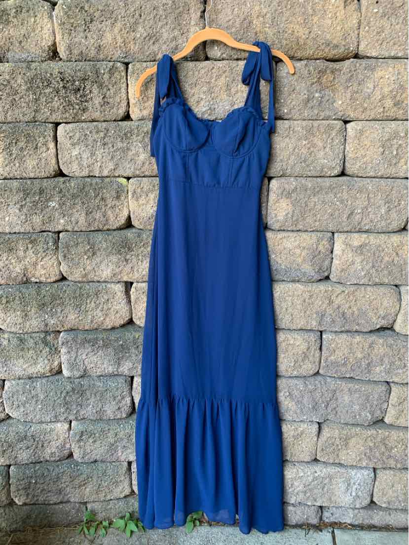 Sleeveless royal blue maxi dress with adjustable shoulder ties and ruffled hem hanging on wooden hanger.