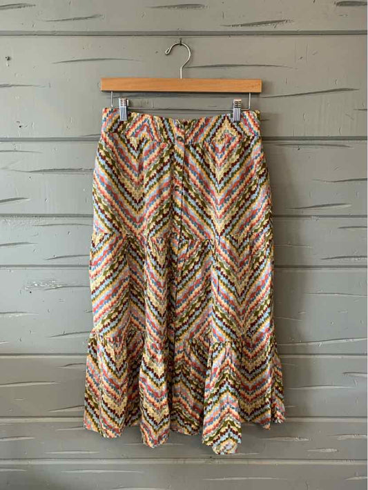 Multicolored zigzag patterned midi skirt with ruffled hem and side pockets hanging on wooden hanger.