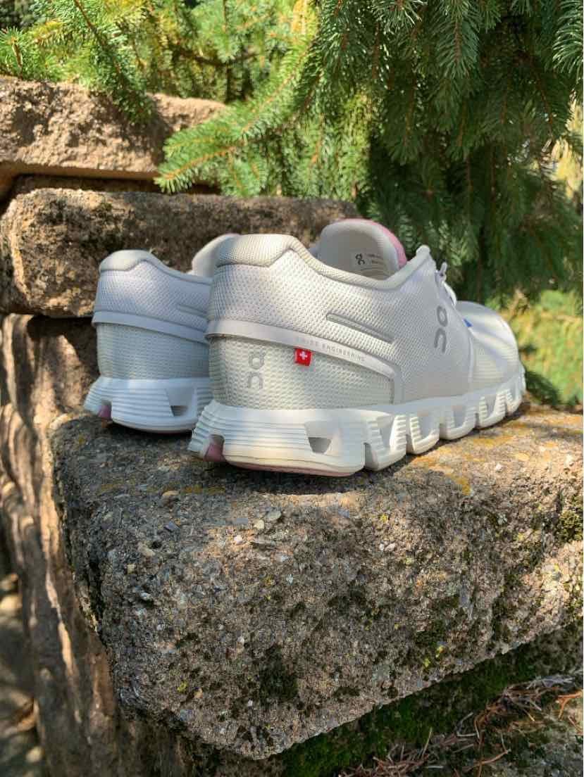 White running sneakers with segmented cushioned sole and subtle branding on heel and side, size 9.