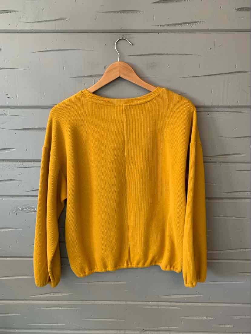 Yellow medium-weight sweater with long sleeves and ribbed cuffs on wooden hanger.