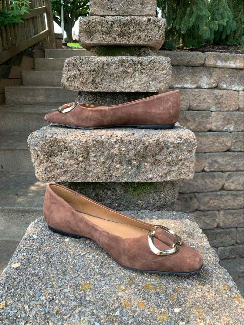 Brown suede pointed-toe flats with gold buckle detail and low heels.