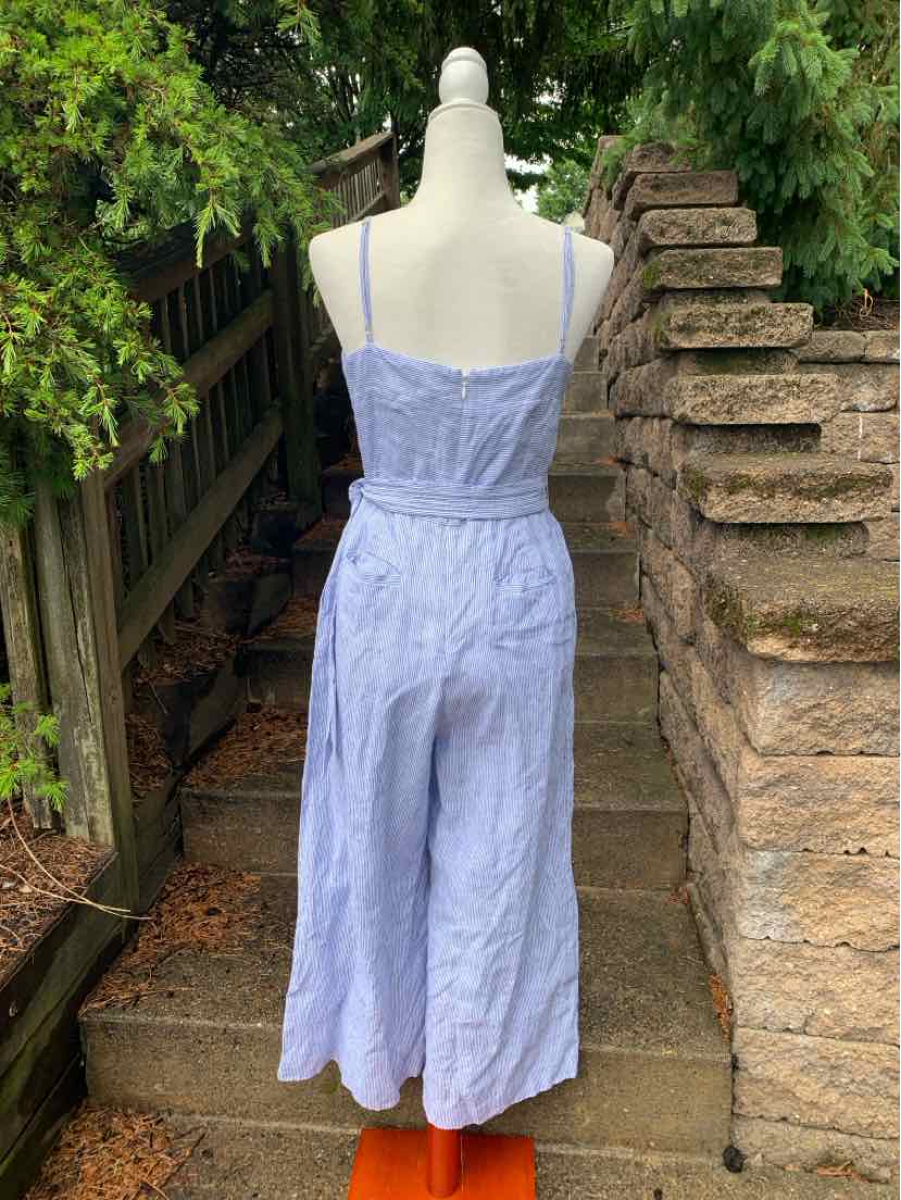 Light blue sleeveless wide-leg jumpsuit with thin straps and cinched waist on a mannequin outdoors.