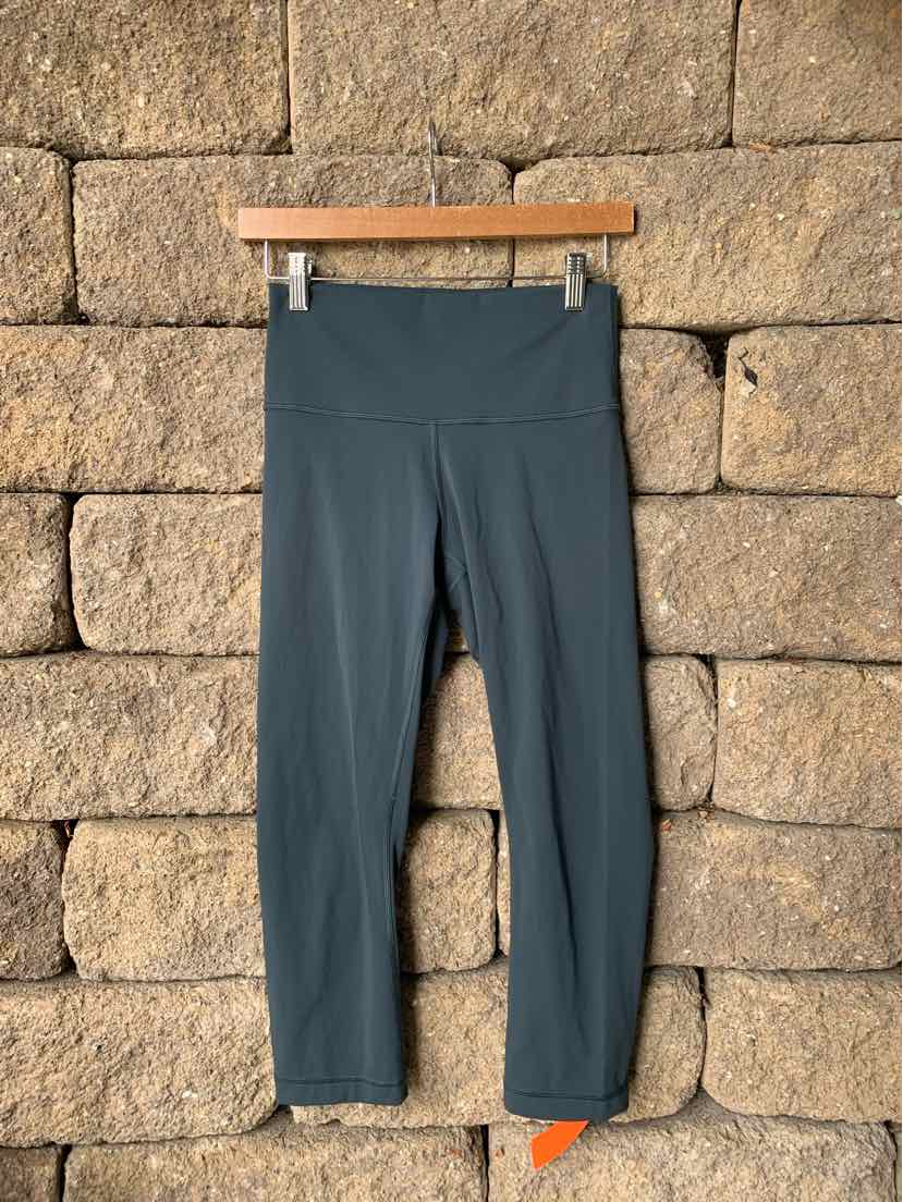 Teal high-waisted cropped leggings with flat seams and smooth, stretchy fabric.