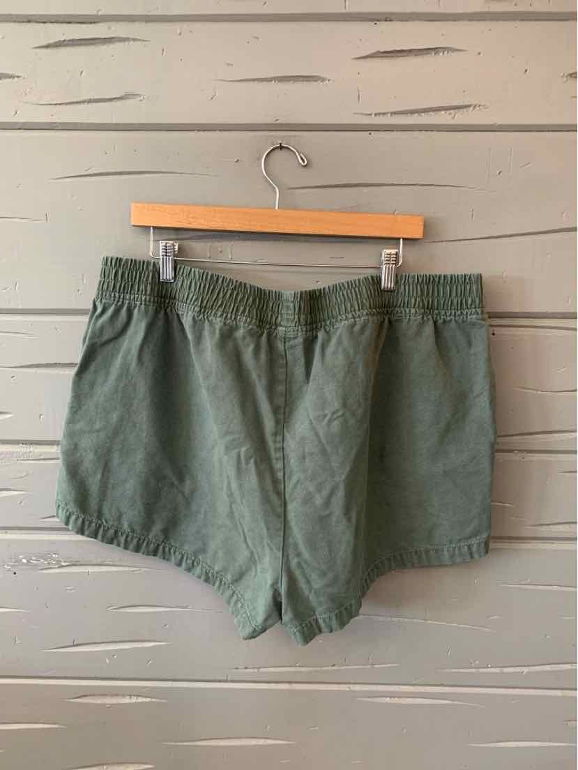 Olive green elastic waistband shorts with a relaxed fit and lightweight fabric, hanging on wooden hanger.
