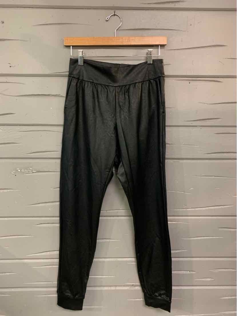 Black high-waist slim-fit pants with elastic waistband and tapered legs hanging on wooden hanger.