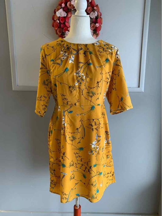 Yellow floral dress with three-quarter sleeves and a gathered neckline on a white mannequin.