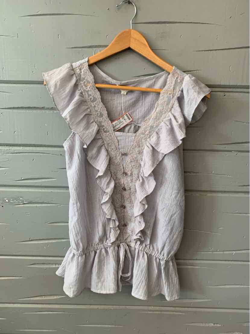 Light gray sleeveless blouse with ruffled V-neckline and peplum hem hanging on wooden hanger.