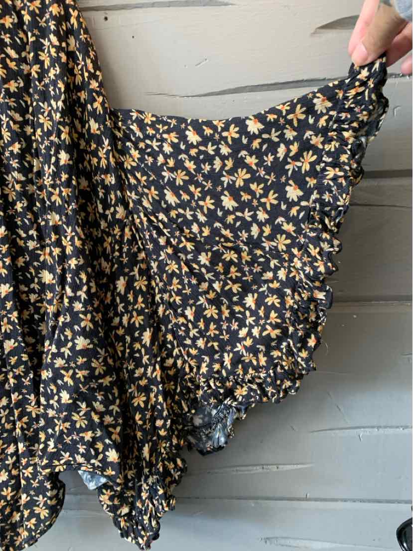 Black skirt with small yellow floral print and ruffled hem, lightweight fabric.