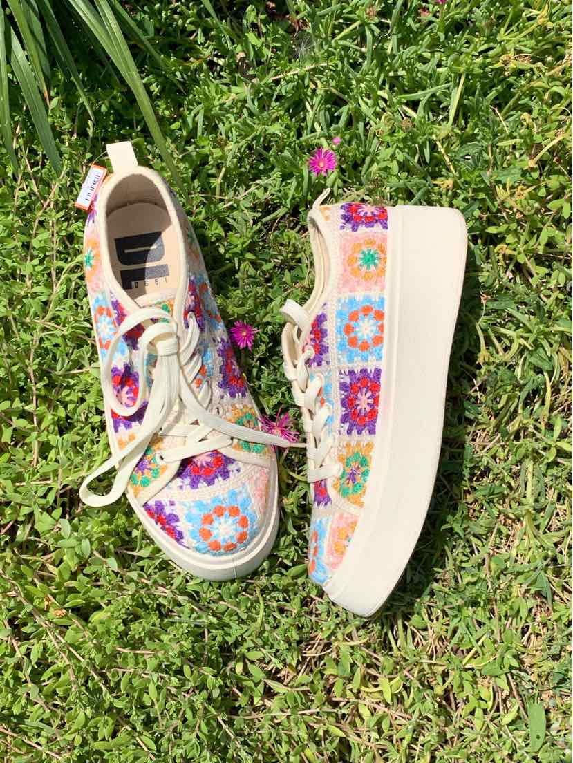 White platform sneakers with colorful crochet flower patches and cream laces.
