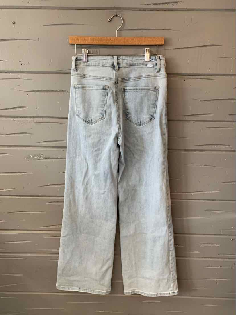 Light blue high-waist straight-leg jeans with back pockets and belt loops hanging on wooden hanger.
