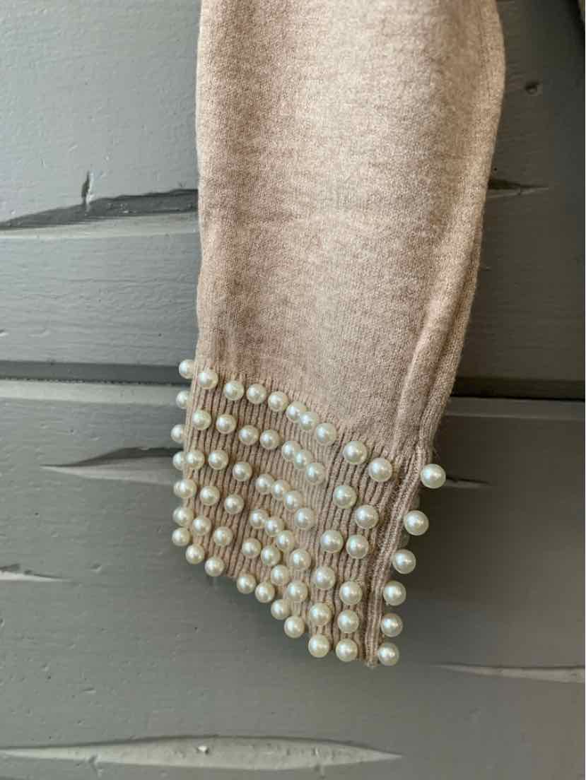 Beige knit sleeve with a tapered cuff embellished with rows of pearl-like beads.