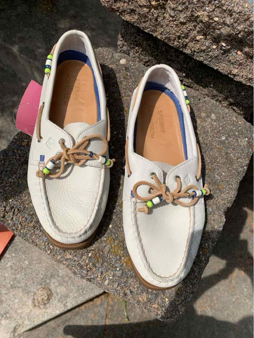 White leather Sperry boat shoes with tan laces and metal eyelets, size 9.5.