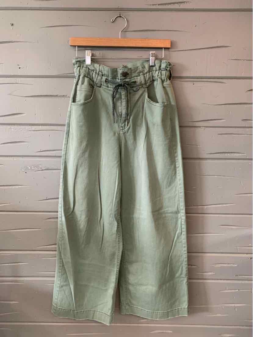 Light green high-waist wide-leg pants with paperbag waist and front pockets hanging on wooden hanger.