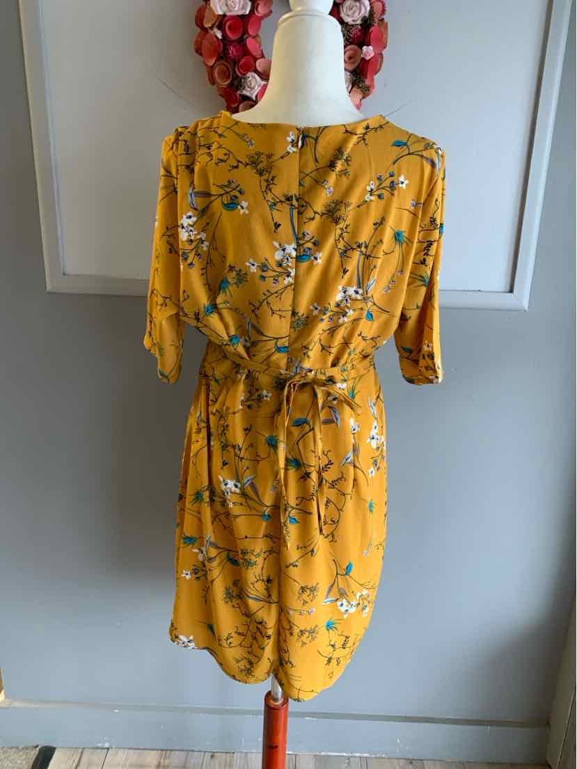 Mustard yellow floral dress with short sleeves, button front, and waist tie belt on mannequin.