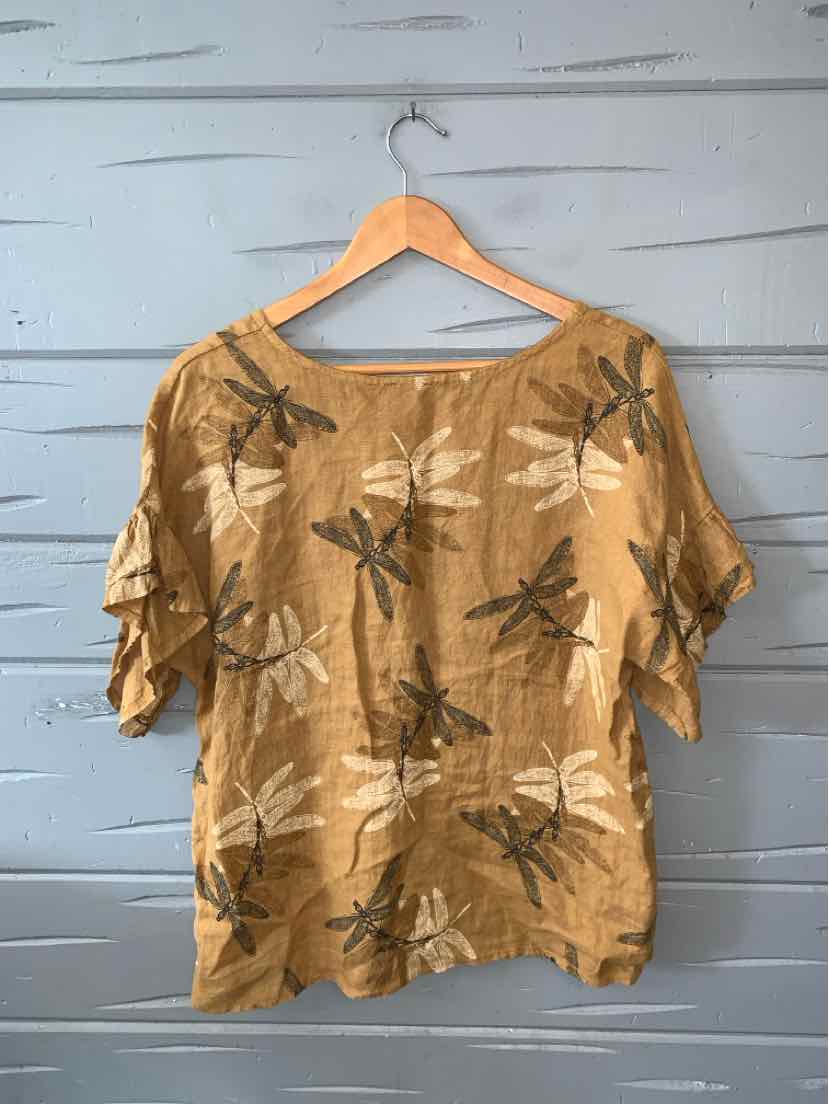 Tan short-sleeve blouse with dragonfly print and loose, relaxed fit on wooden hanger.