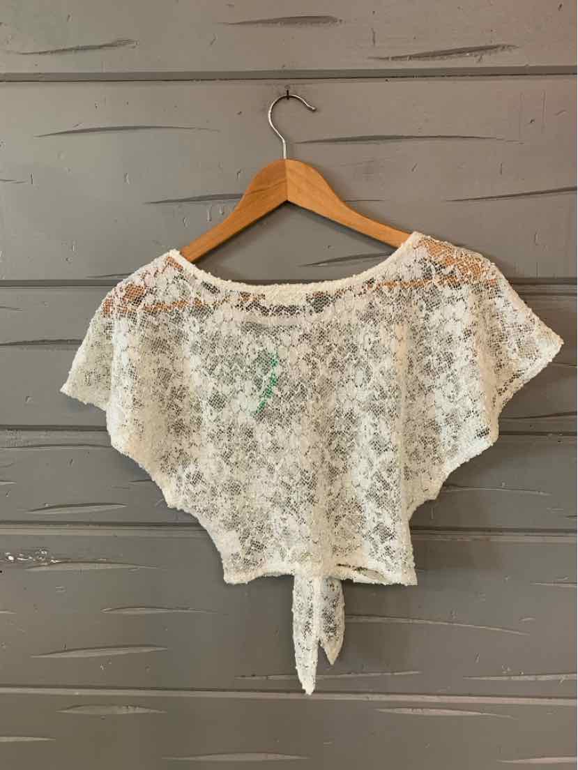 White lace cropped blouse with short sleeves and tie-front detail on wooden hanger.