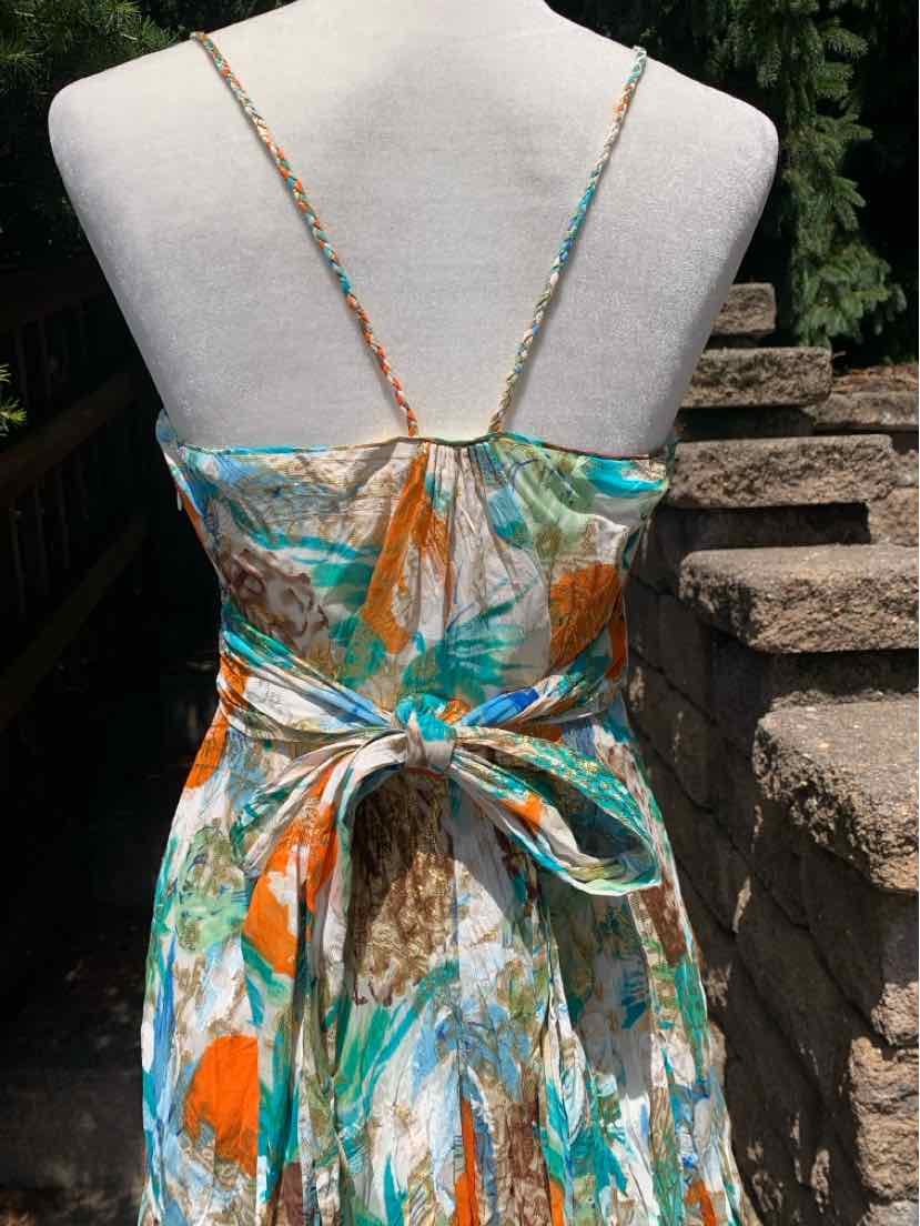 Colorful sleeveless summer dress with thin straps and a large bow tied at the lower back.