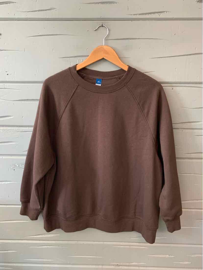 Brown crew neck sweatshirt with long raglan sleeves on wooden hanger against light gray wood panel background.