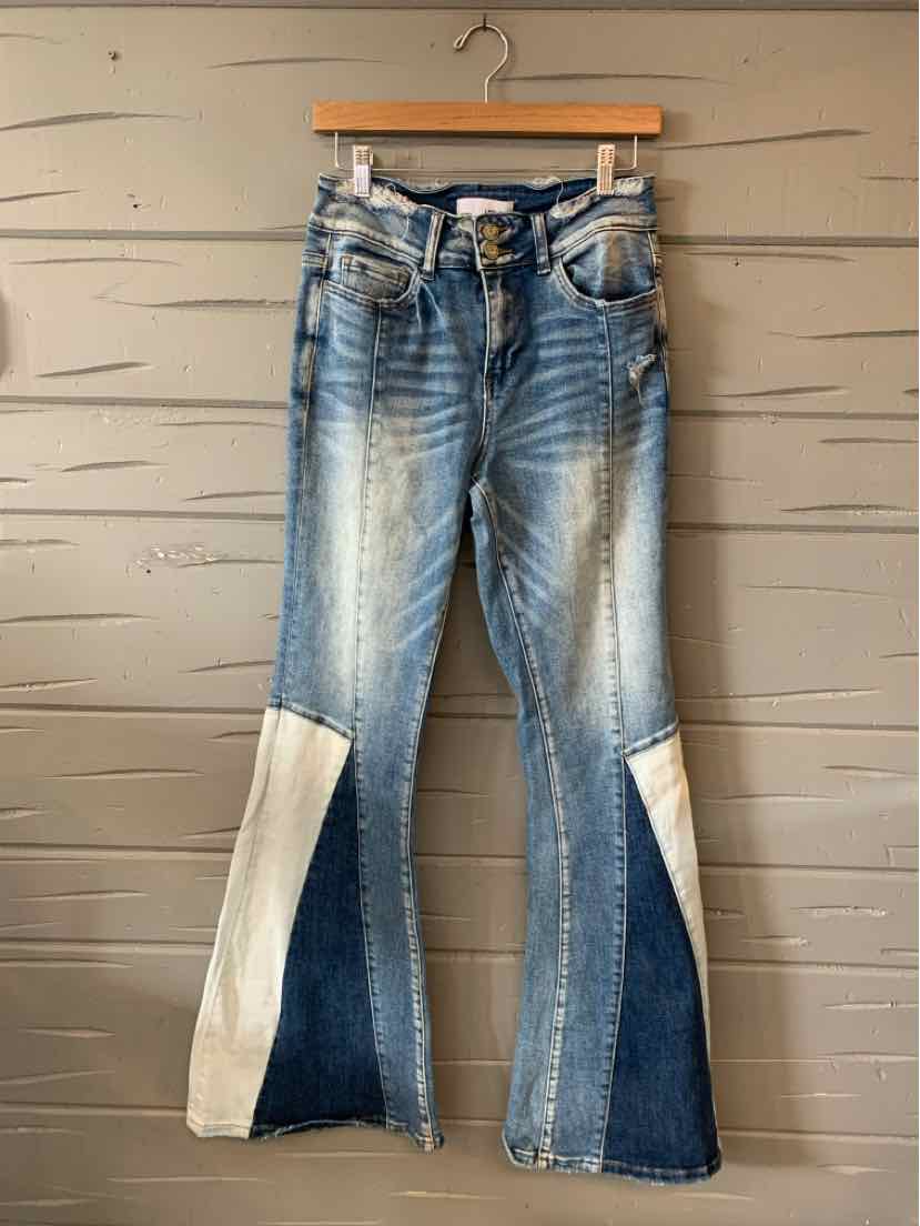 High-waisted flared jeans with blue denim patchwork and light beige fabric panels on lower legs.