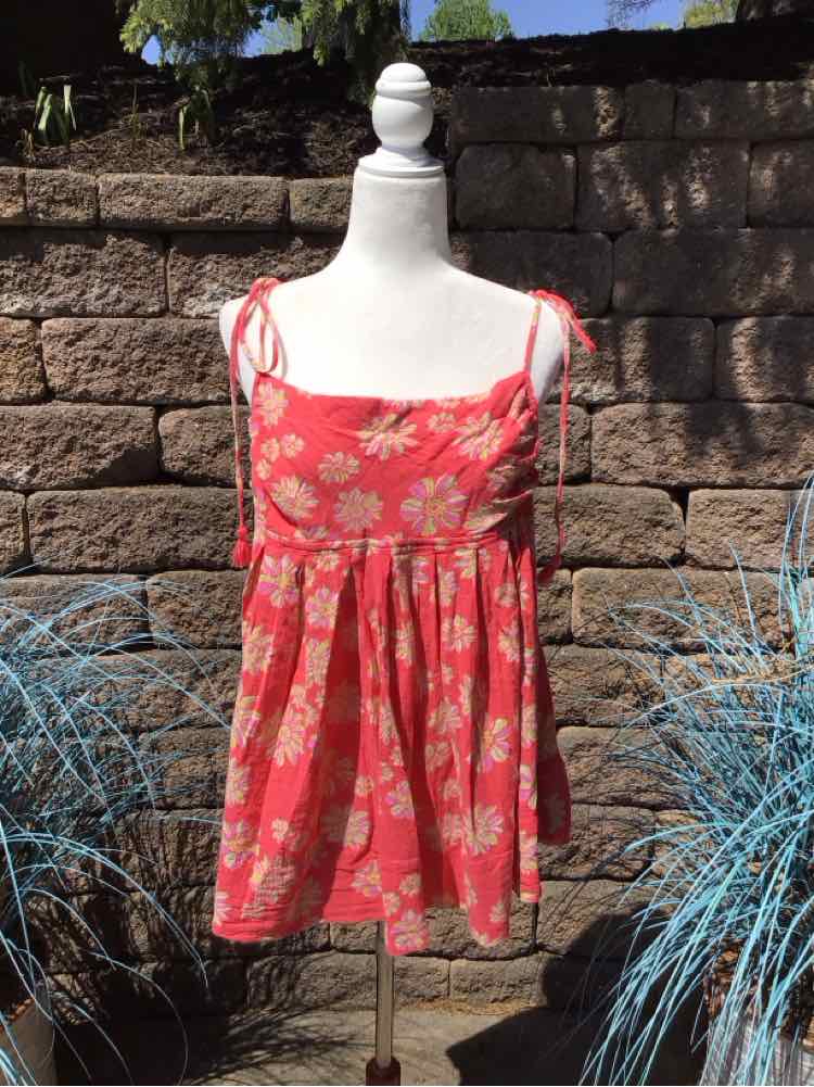 Coral pink floral sundress with adjustable tie straps and smocked bodice on white mannequin.