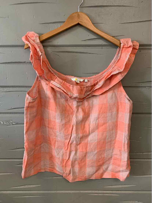 Pink and orange checked sleeveless blouse with ruffled off-shoulder neckline on wooden hanger.