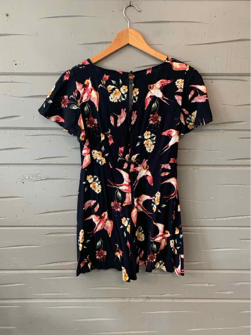 Black short-sleeve romper with colorful bird print and button-up front on wooden hanger.