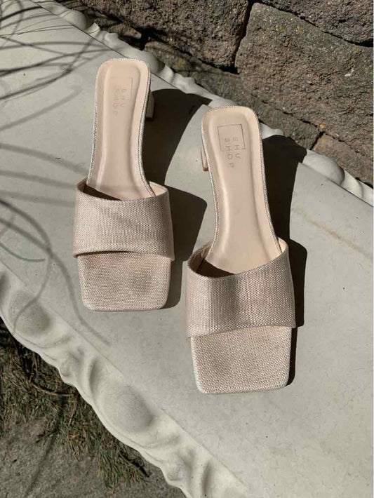 Beige square-toe slip-on sandals with wide fabric straps and flat soles.