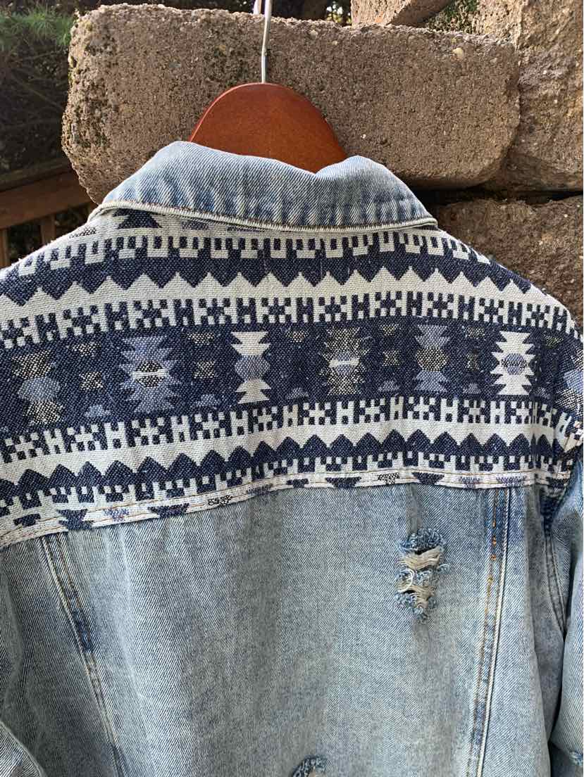Light blue denim jacket with distressed detail and navy white geometric patterned yoke on back.