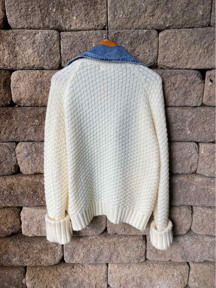 Cream-colored chunky knit sweater with blue denim collar and brown leather patch on back, medium size.