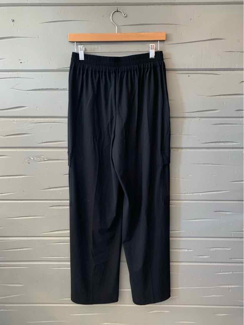 Black Athleta women’s pants with an elastic waistband and relaxed straight legs, hanging on a wooden hanger.