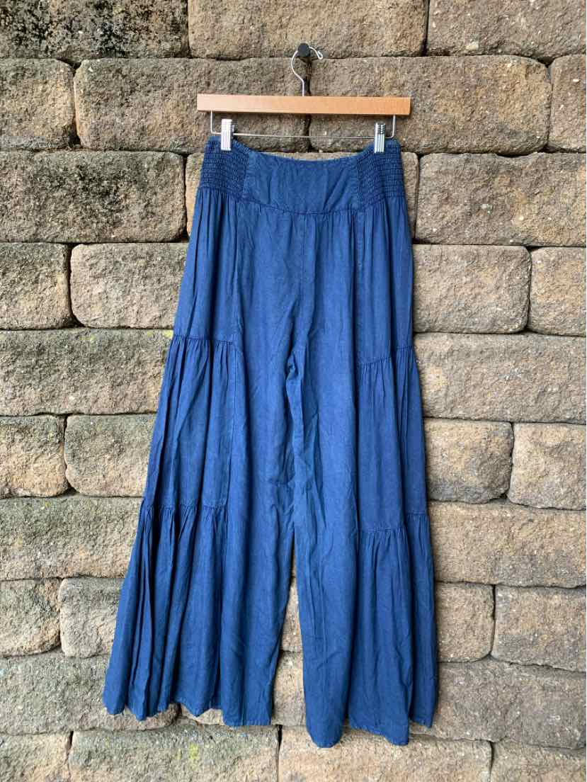 Wide-leg blue pants with tiered, flowing fabric and a high-waist elastic band.