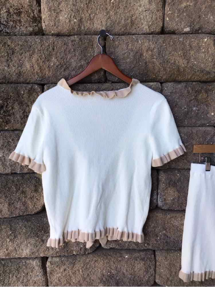 White short-sleeve sweater with beige ruffled trim on collar, sleeves, and hem.