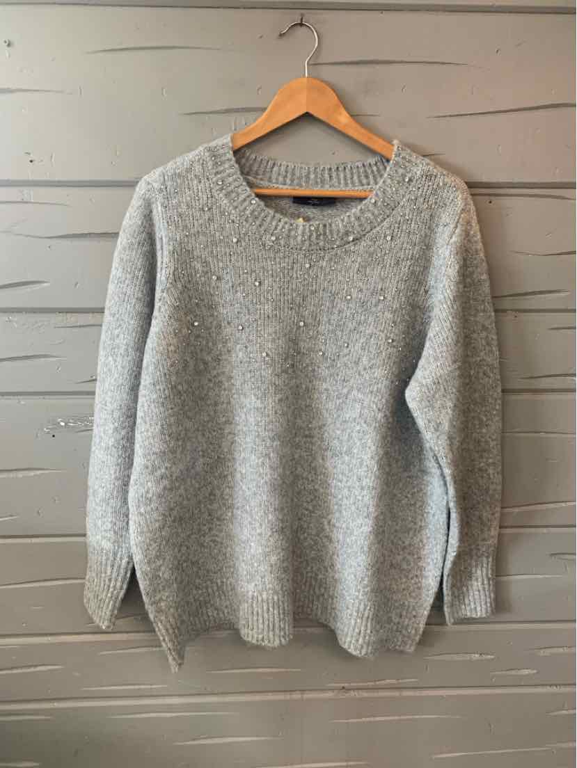 Light gray knit sweater with long sleeves and a wide round neckline hanging on a wooden hanger.