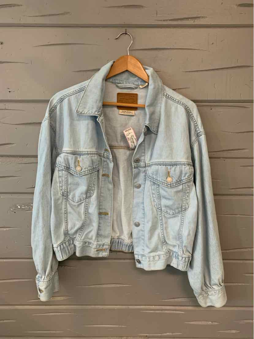 Light wash denim jacket with button-front and chest flap pockets on wooden hanger.