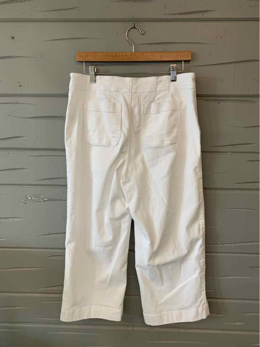 White cropped denim pants with back pockets and straight legs on wooden hanger.