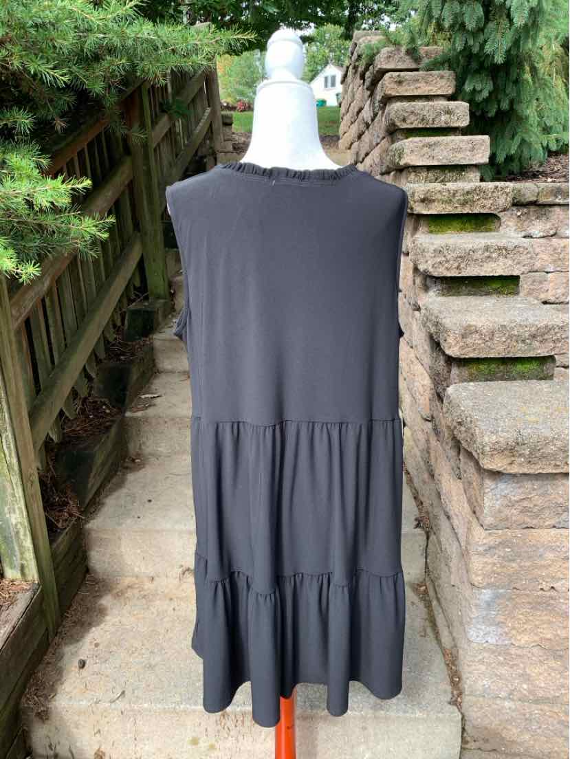 Sleeveless black tiered dress with round neckline and loose fit on mannequin outdoors.