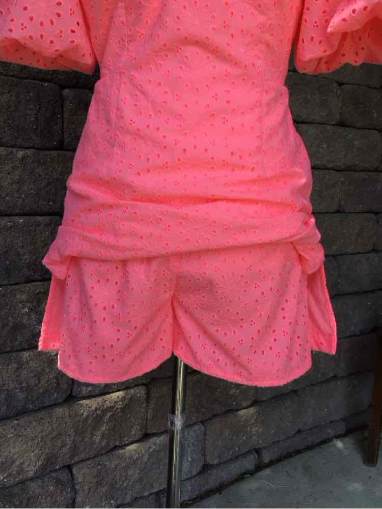 Pink eyelet fabric dress with puffed sleeves and ruched waist detailing.