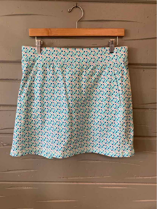 Aqua patterned skirt with small geometric shapes, knee-length, hanging on wooden hanger.