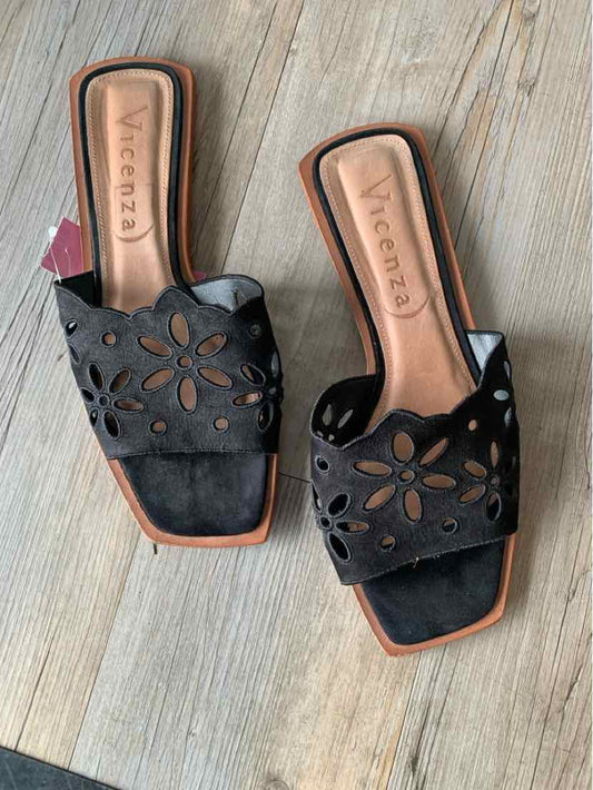 Black open-toe slide sandals with floral cutouts and tan cushioned insoles, size 10.