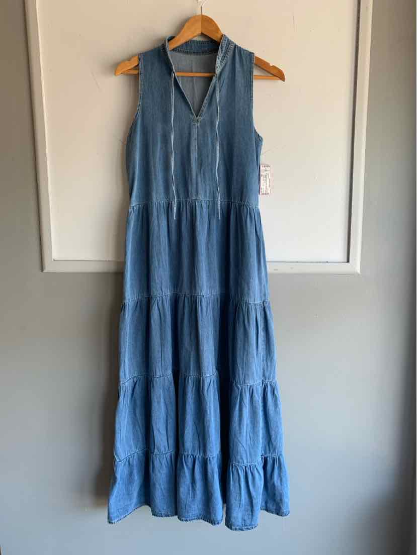 Sleeveless blue denim maxi dress with tiered skirt and V-neck hanging on wooden hanger.