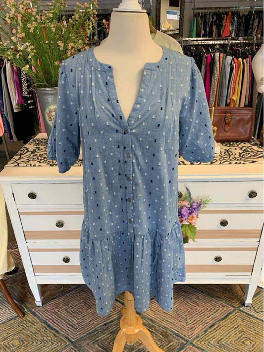 Blue short-sleeve dress with white embroidered dots and tiered hem on mannequin.