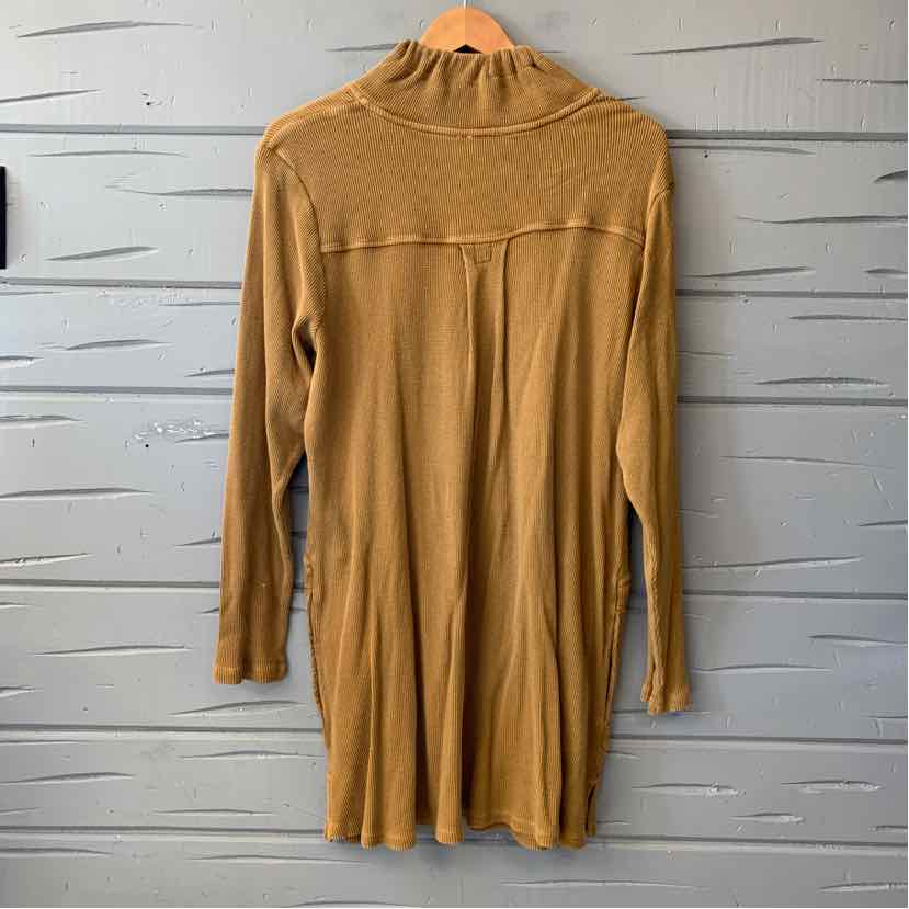 Mustard yellow waffle-knit long-sleeve tunic with a high neckline and a horizontal chest seam, hanging on a wooden hanger.