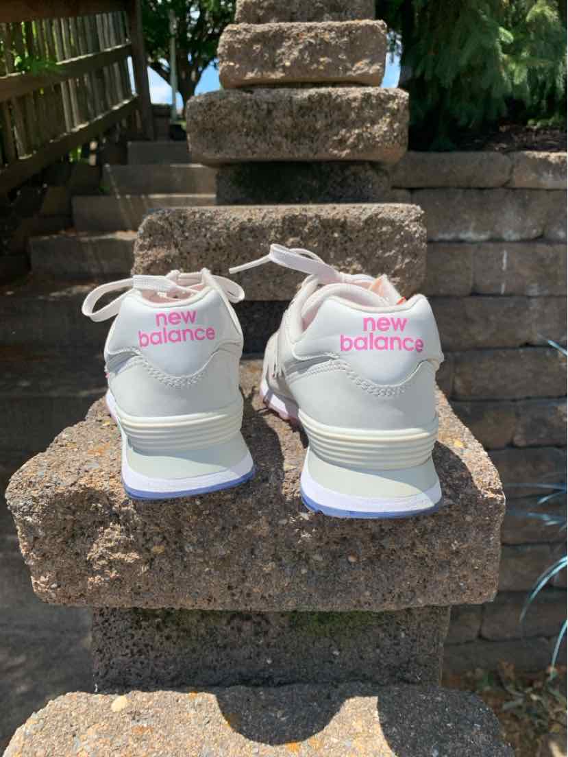 Light gray New Balance sneakers with pink logo on heel, white soles, and white laces, size 9.
