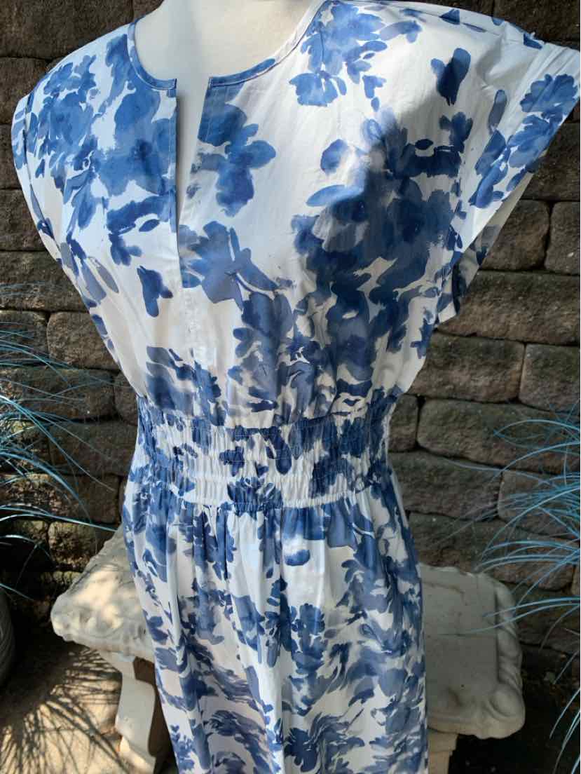 White dress with blue floral print, short sleeves, cinched waist, and round neckline with slit.