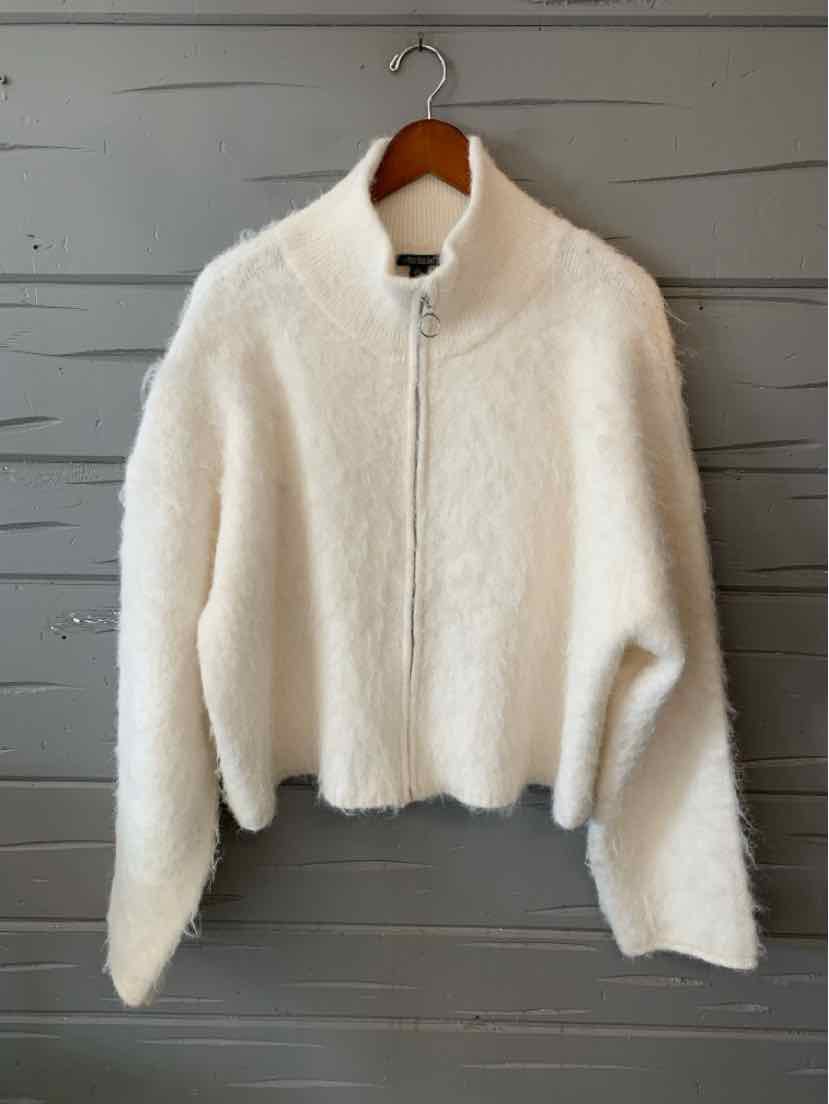 Ivory white fuzzy cropped zip-up jacket with a high collar and long sleeves, hanging on a wooden hanger.