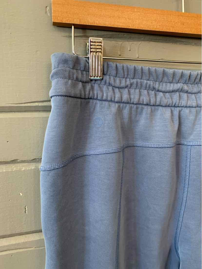 High-waisted blue Lululemon sweatpants in size 8 with elastic waistband and subtle stitching details.