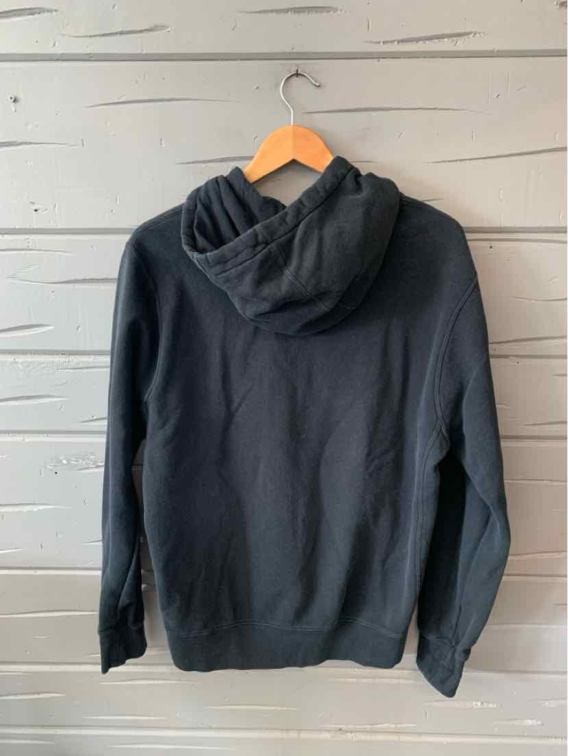 Black Nike hoodie with long sleeves, knit cuffs, and a relaxed fit hanging on wooden hanger.